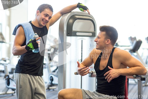 Image of smiling men exercising on gym machine