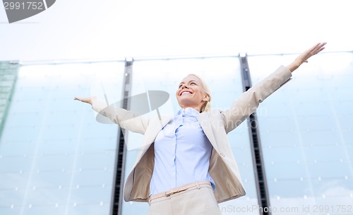 Image of young smiling businesswoman over office building