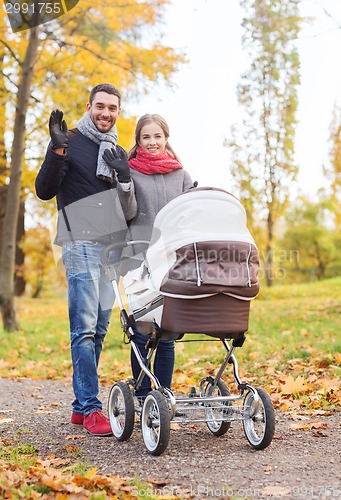 Image of smiling couple with baby pram in autumn park