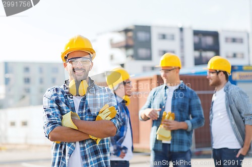 Image of group of smiling builders in hardhats outdoors