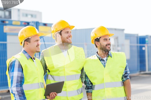 Image of smiling builders in hardhats with tablet pc