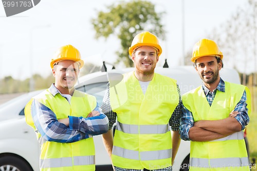 Image of group of smiling builders in hardhats outdoors