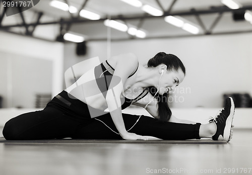 Image of smiling woman stretching on mat in the gym