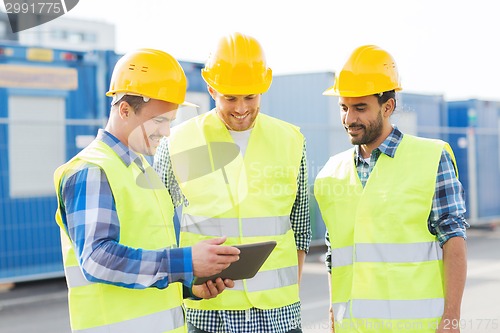 Image of smiling builders in hardhats with tablet pc