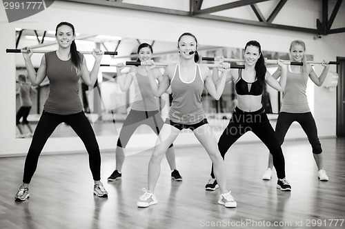 Image of group of smiling people working out with barbells