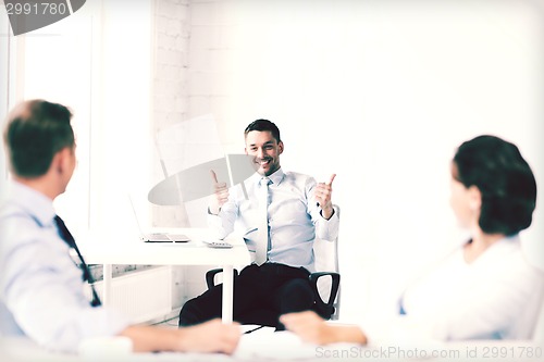 Image of businessman showing thumbs up in office
