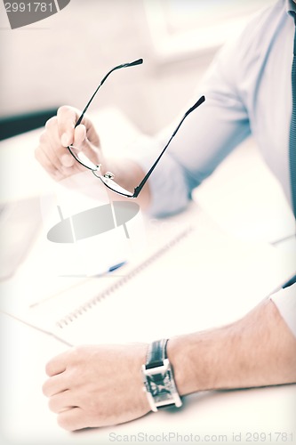 Image of businessman with spectacles writing in notebook