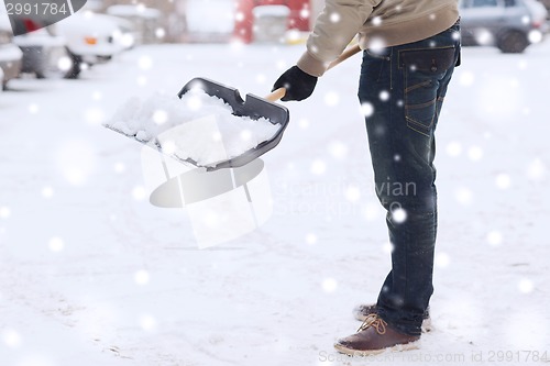 Image of closeup of man digging snow with shovel near car