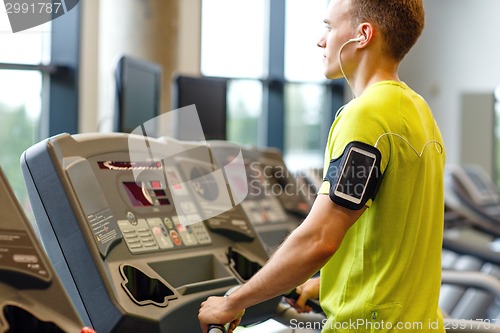 Image of man with smartphone exercising on treadmill in gym