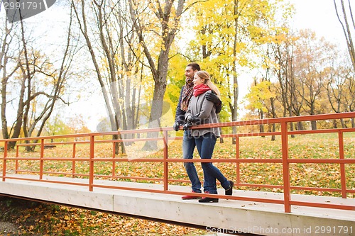 Image of smiling couple hugging on bridge in autumn park