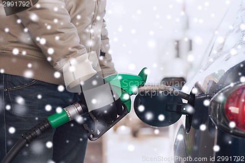 Image of close up of man with fuel hose nozzle tanking car