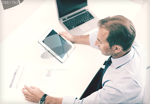 Image of businessman with tablet pc and papers in office