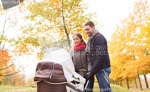 Image of smiling couple with baby pram in autumn park