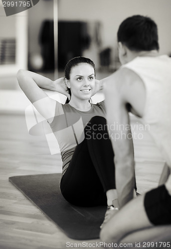 Image of male trainer with woman doing sit ups in the gym