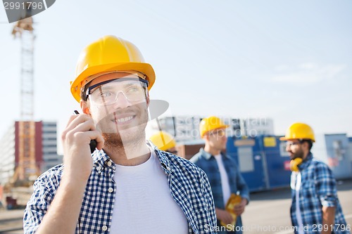 Image of group of smiling builders in hardhats with radio