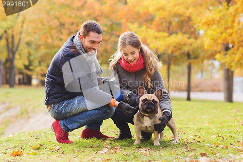 Image of smiling couple with dog in autumn park