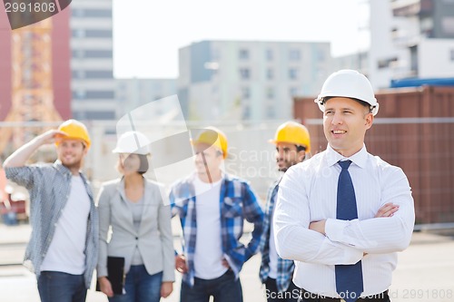 Image of group of smiling builders in hardhats outdoors