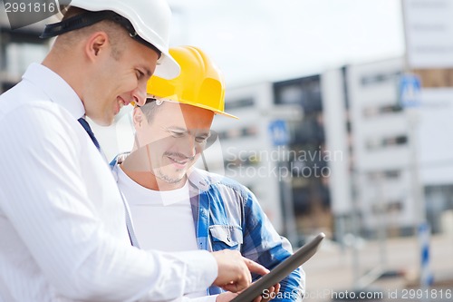 Image of smiling builders in hardhats with tablet pc