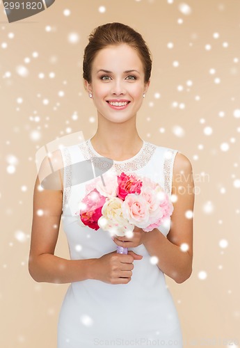 Image of smiling woman in white dress with bunch of flowers