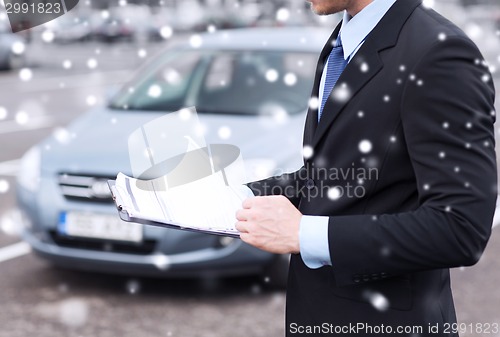 Image of close up of man with clipboard and car documents