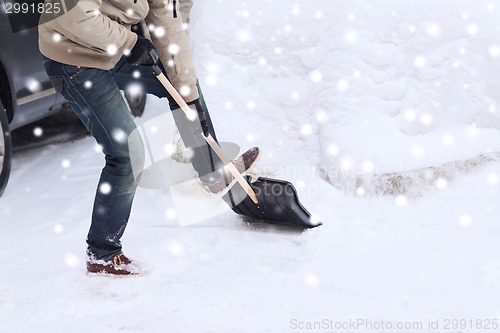 Image of closeup of man digging snow with shovel near car