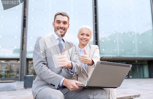 Image of smiling businesspeople with laptop outdoors