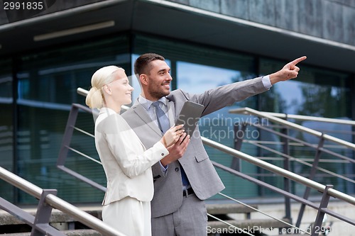 Image of smiling businessmen with tablet pc outdoors
