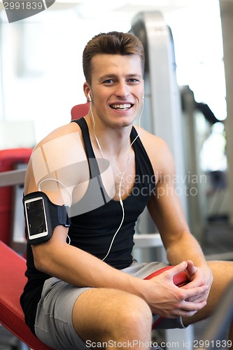 Image of smiling sportsman with smartphone and earphones