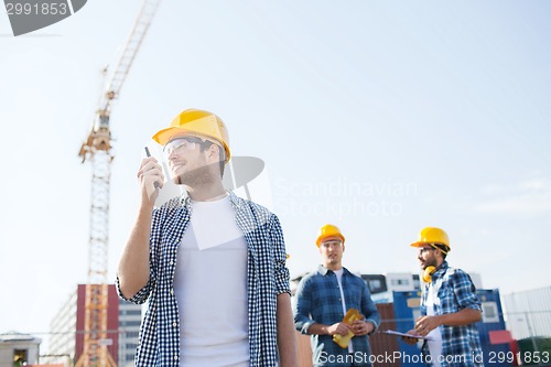 Image of group of smiling builders in hardhats with radio