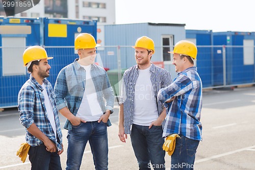 Image of group of smiling builders in hardhats outdoors