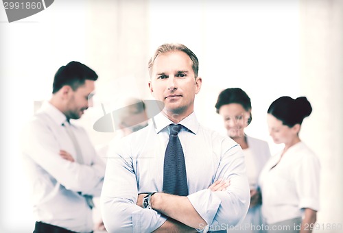 Image of handsome businessman with team in office