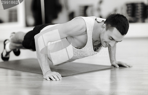 Image of smiling man doing push-ups in the gym