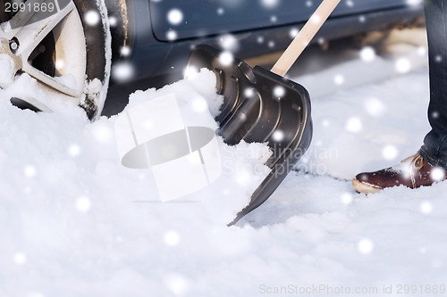 Image of closeup of man digging snow with shovel near car