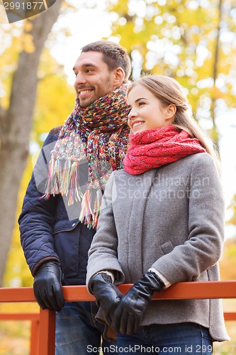 Image of smiling couple hugging on bridge in autumn park