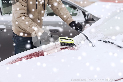 Image of closeup of man cleaning snow from car