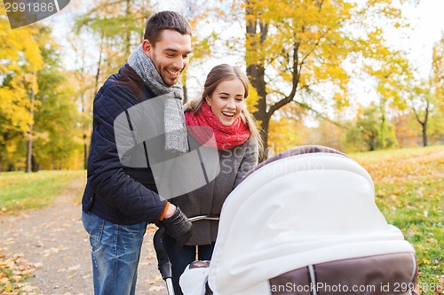 Image of smiling couple with baby pram in autumn park