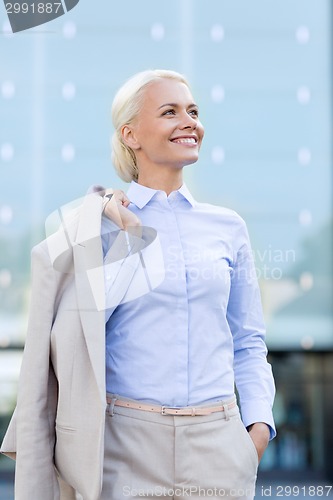 Image of young smiling businesswoman over office building