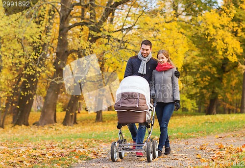 Image of smiling couple with baby pram in autumn park