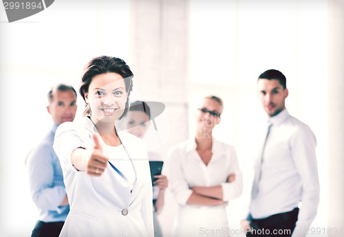 Image of businesswoman in office showing thumbs up