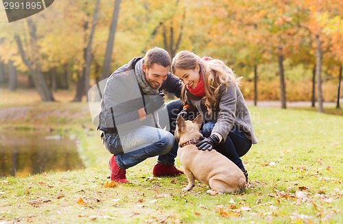 Image of smiling couple with dog in autumn park