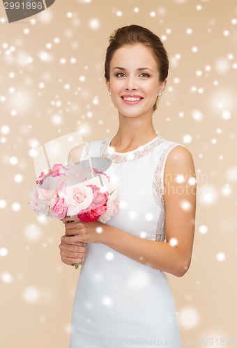 Image of smiling woman in white dress with bunch of flowers