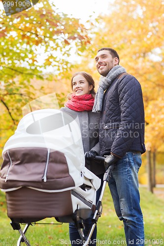 Image of smiling couple with baby pram in autumn park