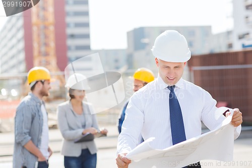 Image of group of builders with tablet pc and blueprint