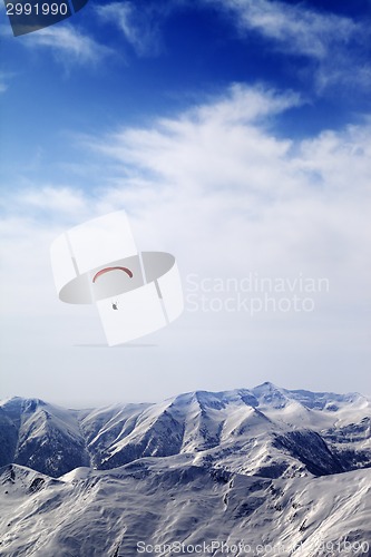 Image of Parachutist silhouette of mountains in windy sky