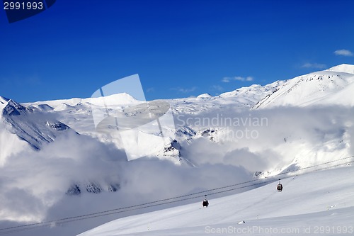 Image of Off-piste snowy slope and cable car at sun day