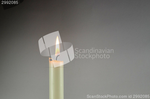 Image of One white candle at grey background