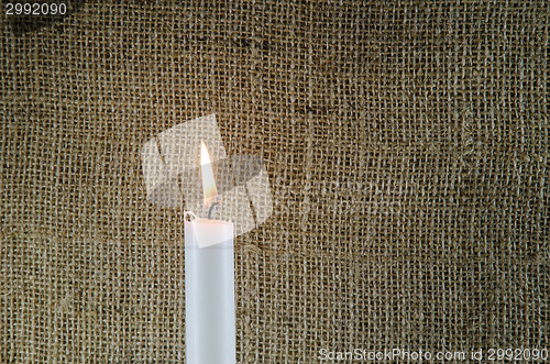 Image of Burning candle with burlap background