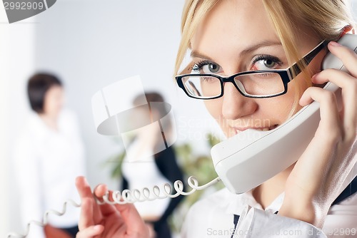 Image of Attractive woman calls by wire phone in office