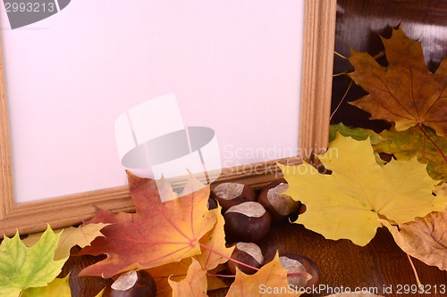 Image of autumn chestnuts on wooden background and blank paper card