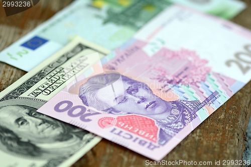 Image of dollars euro and hryvnia banknotes on wooden background